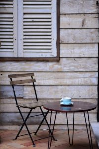 n-empty-wooden-chair-or-simple-stool-in-soft-natural-light-with-an-unfinished-cup-of-coffee-nearby
