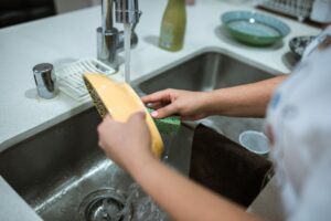 A-pair-of-hands-washing-a-single-dish-in-a-kitchen-sink