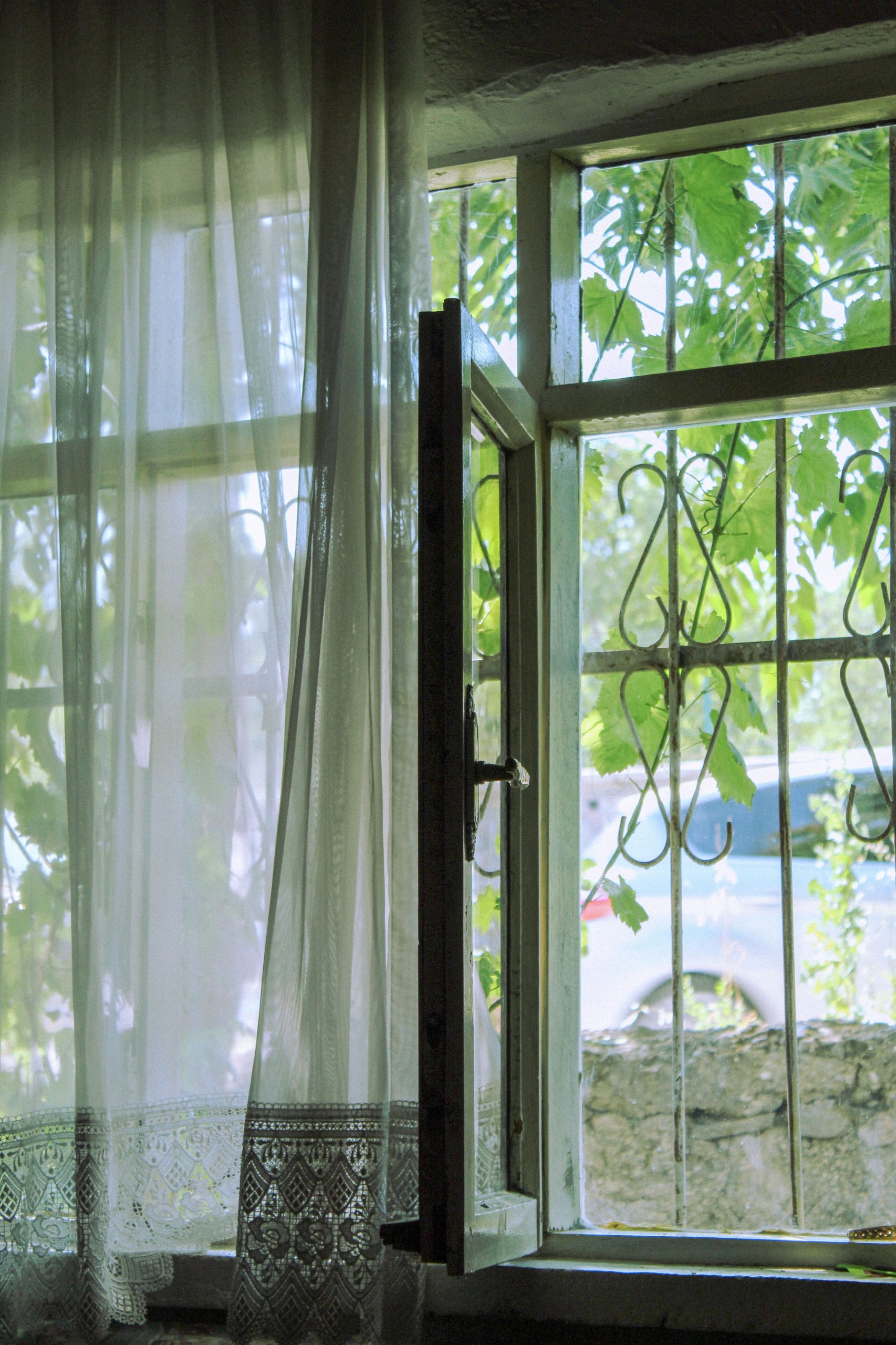 An-open-window-with-a-light-sheer-curtain-lifting-gently-in-the-breeze