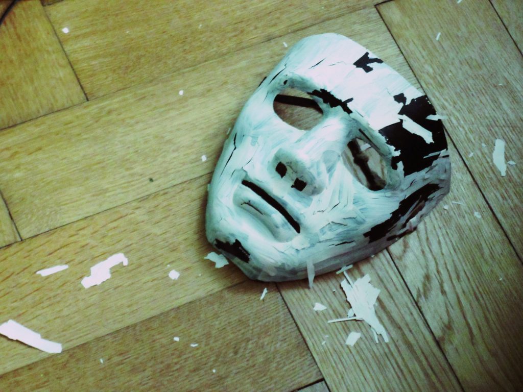 theatrical-mask-laid-face-down-on-a-plain-wooden-table