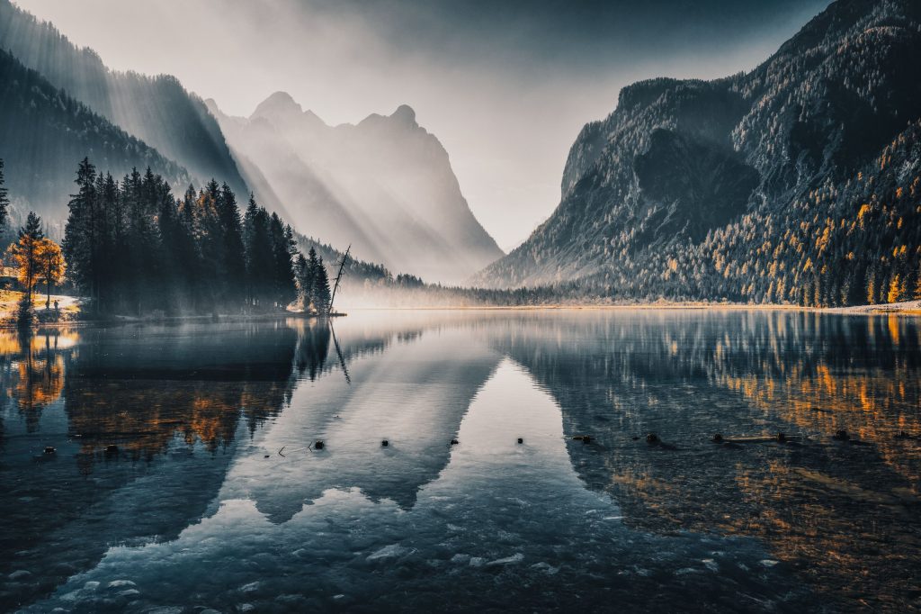 A-still-mountain-lake-at-dawn-utterly-quiet-with-a-massive-mountain-behind-it