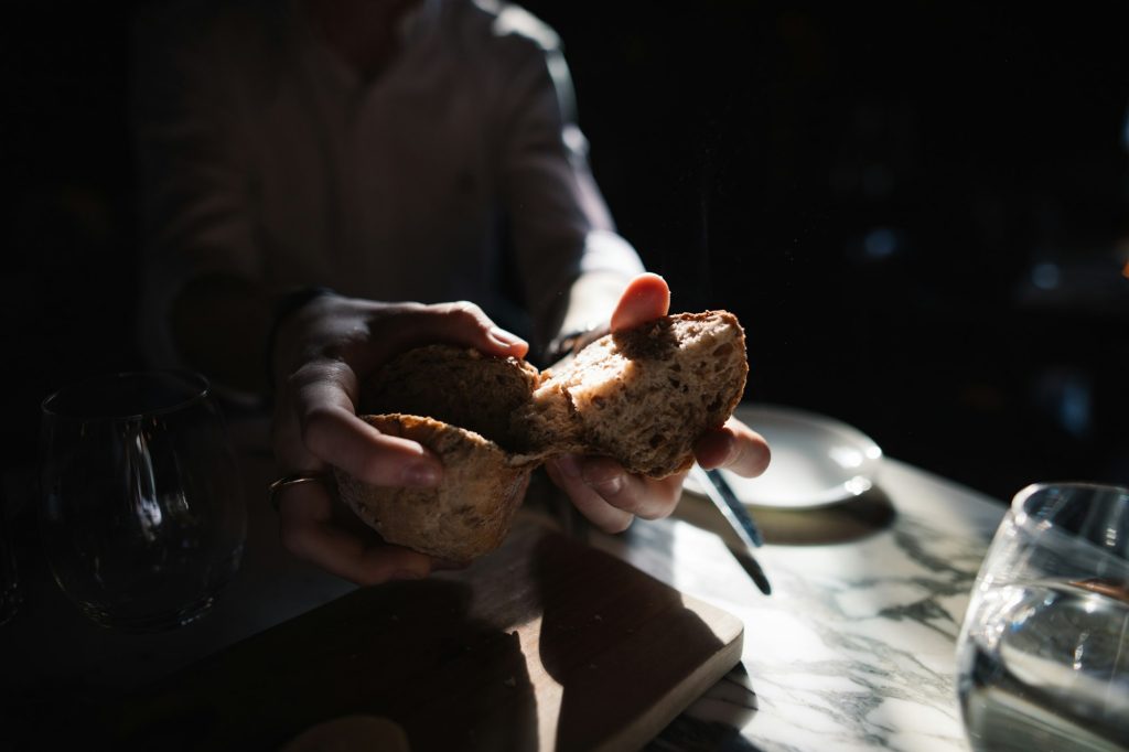 Two hands breaking a loaf of bread